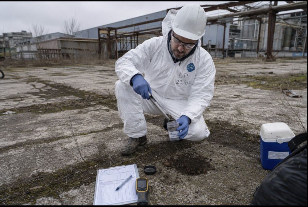 Technicien en combinaison prélevant un échantillon de sol sur site